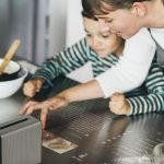 Mutter und Tochter beim Kochen mit projizierter Kochanleitung auf der Arbeitsfläche