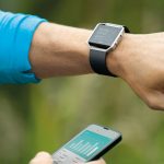 Sportler mit Fitnesstrecker und App auf Smartphone