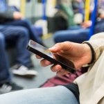 Mann mit Smartphone in der Bahn