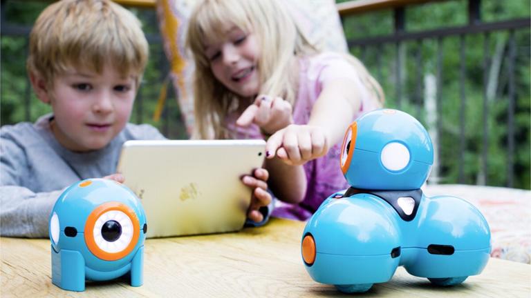 Mädchen und Junge spielen mit Roboter Dot