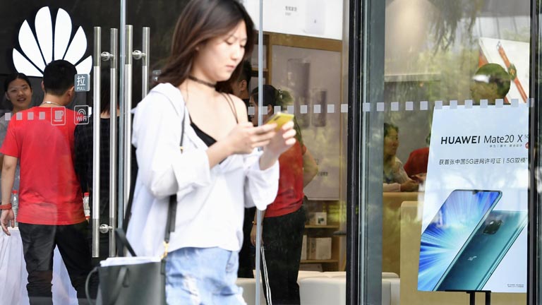 Frau vor Huawei Store mit Smartphone in der Hand