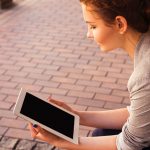 Frau tippt lächelnd auf Tablet