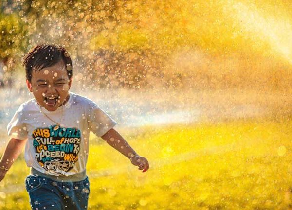 Junge läuft lachend durch Sommerregen