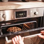 Eine Person öffnet einen Backofen, in dem ein Kuchen gebacken wird.