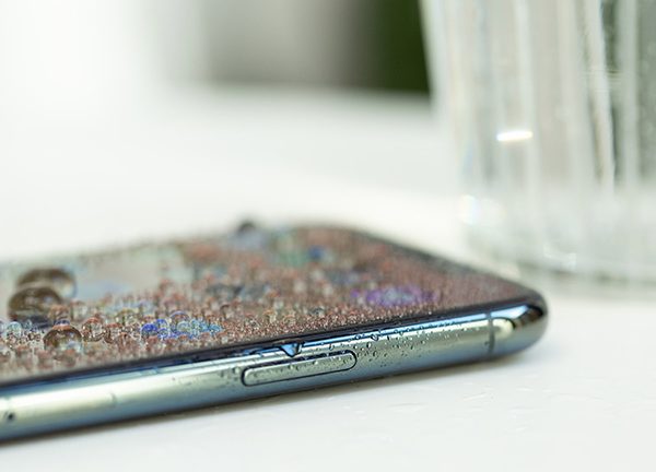 Das iPhone 11 ist mit Wasser bedeckt. Daneben steht ein Glas.