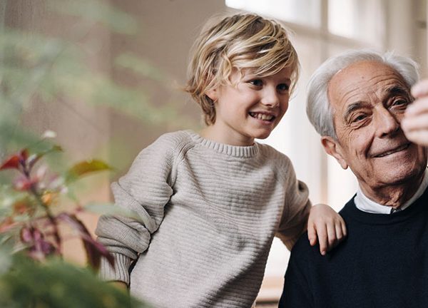 Ein Senior und ein Kind schauen zusammen auf ein Smartphone.