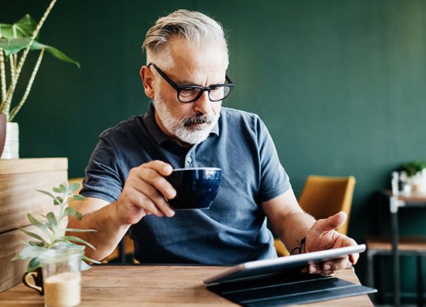 Eine Person sitzt in einem Café und bedient ihr iPad.