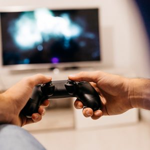 Eine Person hält einen PS4-Controller in der Hand und spielt etwas.