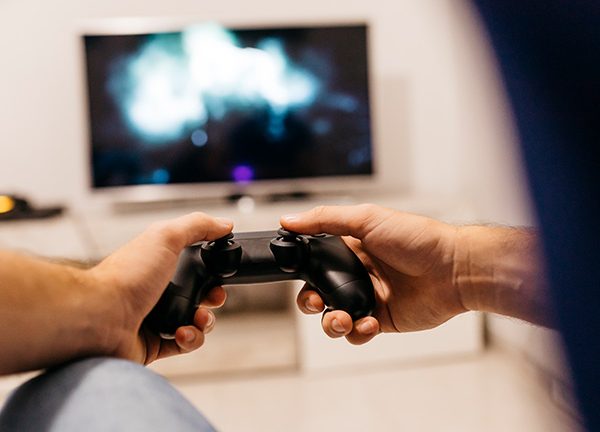 Eine Person hält einen PS4-Controller in der Hand und spielt etwas.