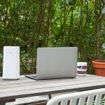 Ein Huawei GigaCube 5G steht auf einem Terrassen-Tisch im Garten neben einem Notebook.