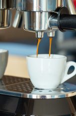 Langsam läuft Espresso von einer Kaffeemaschine in eine kleine Espresso-Tasse.