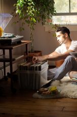 Zwei Personen sitzen auf dem Fußboden vor einer Plattenkiste und schauen sich die Schallplatten an.