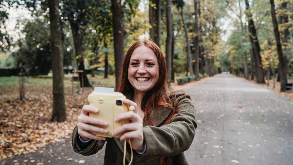 Eine Person nimmt ein Selfie mit einer Sofortbildkamera auf.