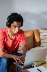 Eine Person mit Kopfhörern auf dem Kopf sitzt vor einem MacBook.