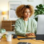 Eine Person sitzt an einem Schreibtisch vor einem PC.