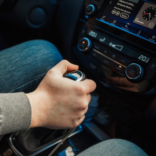 Eine Person betätigt die Gangschaltung in ihrem Auto.