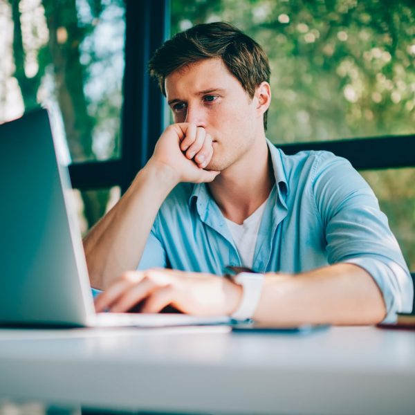 Eine Person sitzt vor einem Laptop und blickt angestrengt auf den Bildschirm.