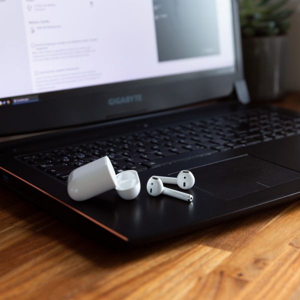 AirPods und das dazugehörige Case liegen auf einem Windows-Laptop.