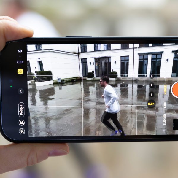 Ein iPhone 14 Pro mit eingeschaltetem Actionmodus filmt eine vorbeilaufende Person.