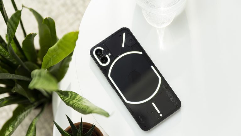 Ein Nothing Phone (1) mit leuchtender Rückseite liegt auf einem weißen Tisch.