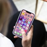 Eine Person hält ein iPhone in der Hand, auf dem gerade Apps gelöscht oder verschoben werden sollen.