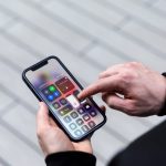 Eine Person tippt auf ein iPhone, auf dem das Kontrollzentrum geöffnet ist.