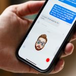 Eine Person hält ein iPhone in der Hand, auf der ein Memoji den Gesichtsausdruck der Person nachahmt.