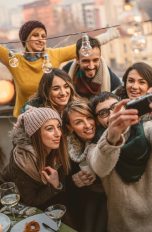 Eine Gruppe Personen in Winterkleidung posiert gemeinsam auf einer Dachterrasse für ein Gruppenselfie.