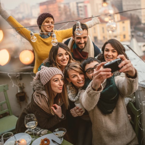 Eine Gruppe Personen in Winterkleidung posiert gemeinsam auf einer Dachterrasse für ein Gruppenselfie.