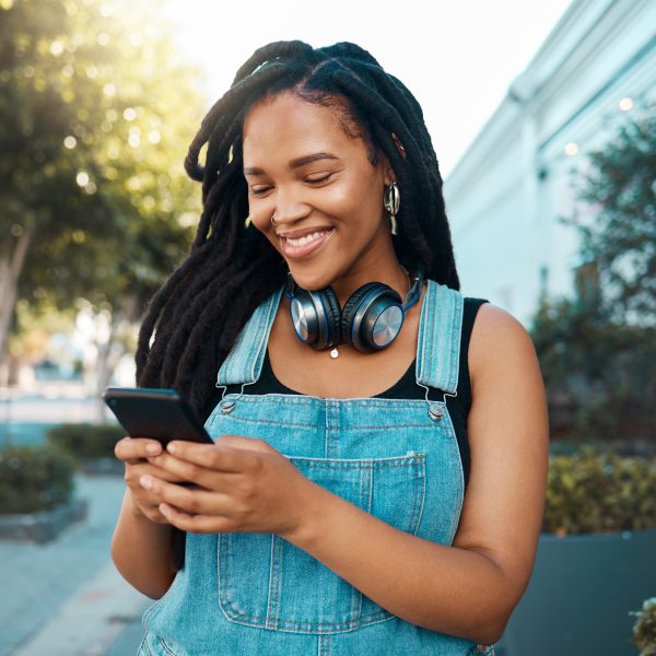 Eine Person mit Kopfhörern um den Hals schaut auf ihr Smartphone.