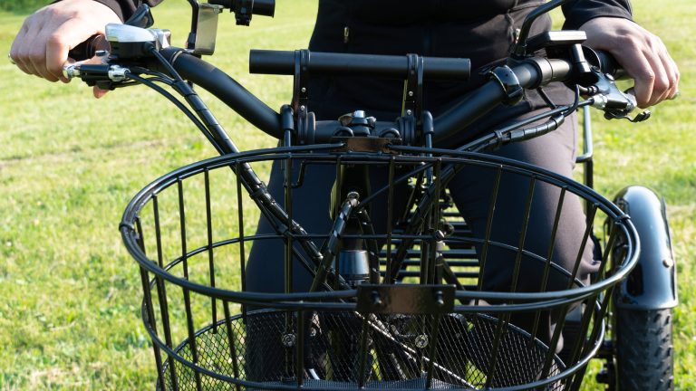 Der Lenker eines E-Bikes mit einem Fahrradkorb und mehreren kleinen Anbauten für Kabel und Kameras.