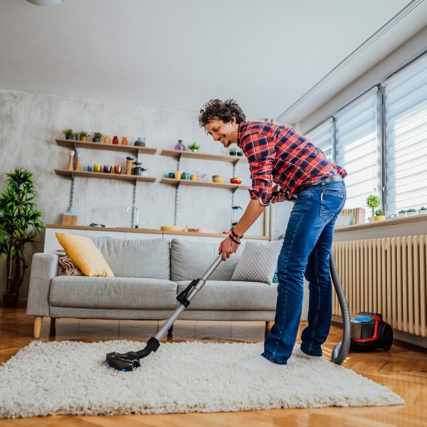 Eine Person saugt in ihrem Wohnzimmer den Teppich.