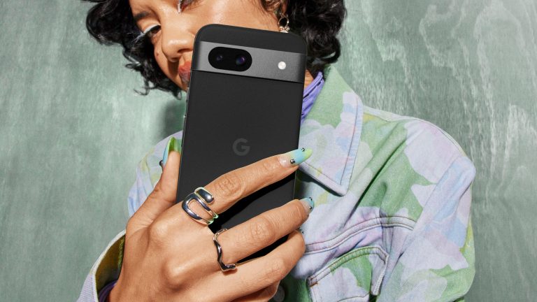 Eine Person hält ein schwarzes Google Pixel 8a in die Kamera.