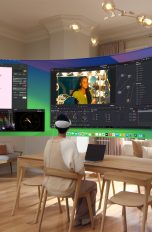 Eine Person sitzt in ihrem Wohnzimmer und hat eine Apple Vision Pro Brille auf. Vor ihr schwebt ein Ultra Wide Screen mit mehreren offenen Apple Apps.