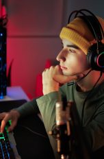 Eine Person mit Headset auf dem Kopf sitzt vor einem Gaming-Rechner.