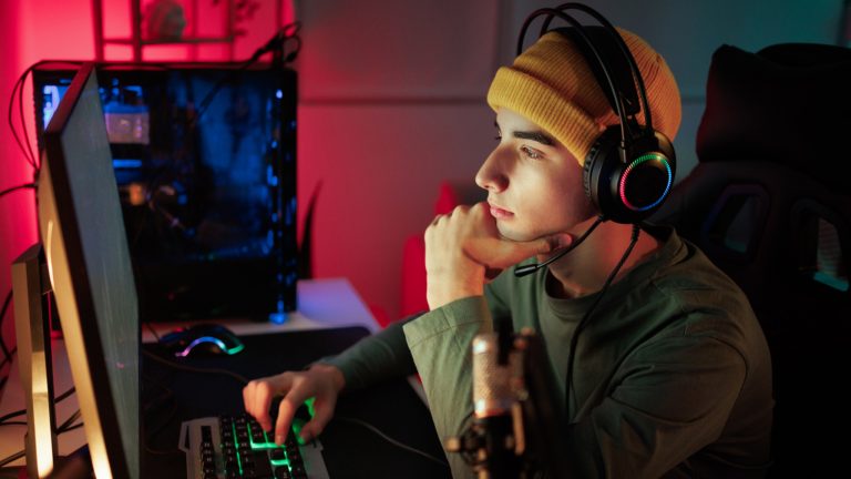 Eine Person mit Headset auf dem Kopf sitzt vor einem Gaming-Rechner.