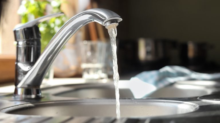 Blick auf eine Armatur in der Küche, aus deren Wasserhahn Wasser läuft.