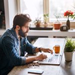 Eine Person sitzt an einem Schreibtisch vor einem MacBook Pro.