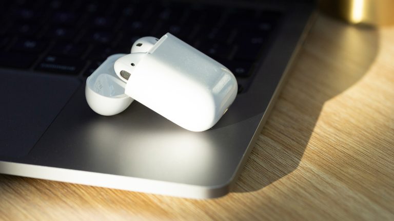 Zwei AirPods liegen in einem Ladecase auf einem Laptop.