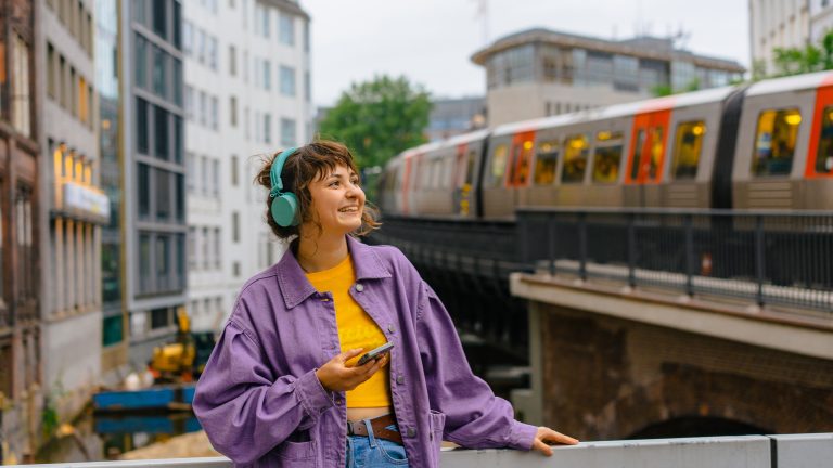 Eine Person ist in Hamburg unterwegs und hört dabei per Smartphone und Kopfhörer Musik.