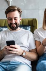 Zwei Personen sitzen nebeneinander auf einem Sofa und schauen in ihre Smartphones.