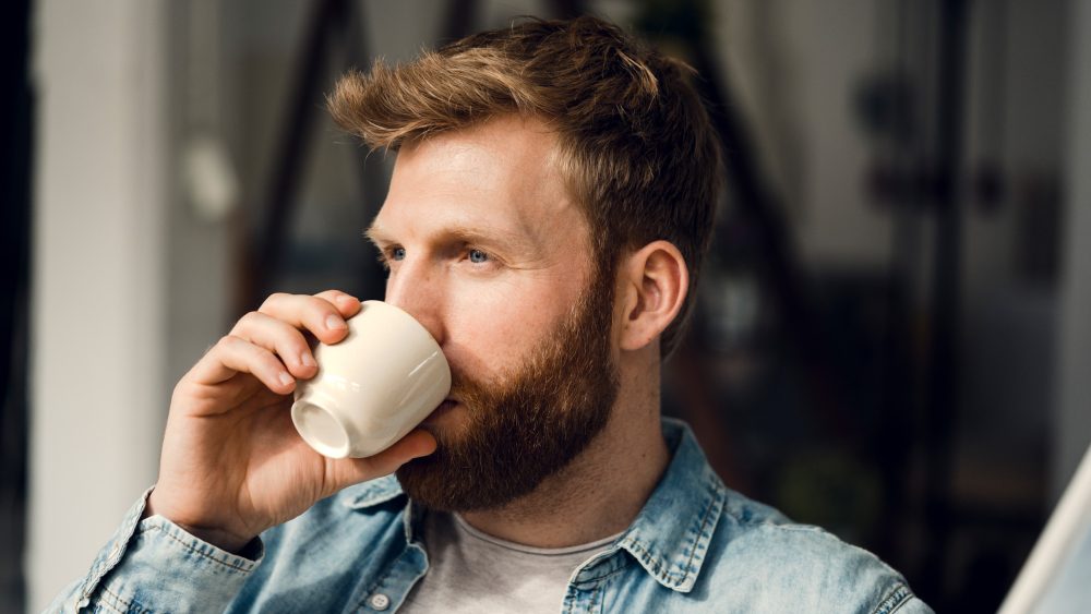 Eine Person trinkt aus einer Kaffeetasse.