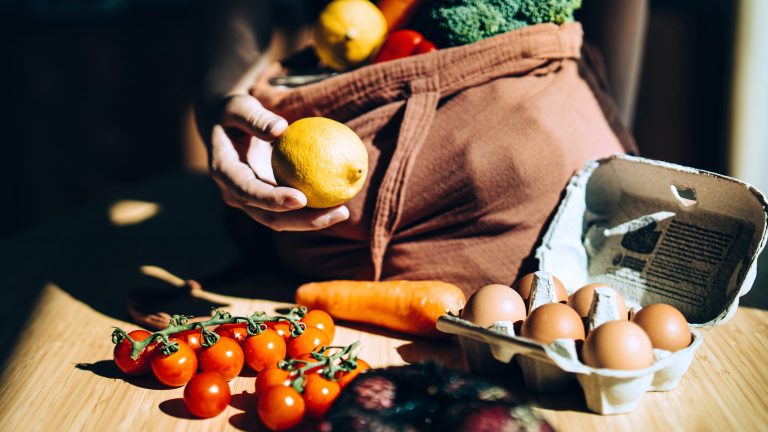 Obst, Gemüse und Eier werden aus einer Einkaufstüte geräumt.