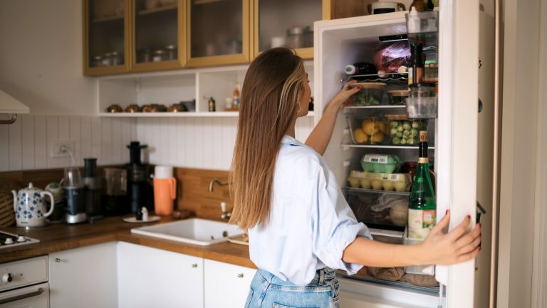 Eine Person nimmt etwas aus einem Einbaukühlschrank heraus.