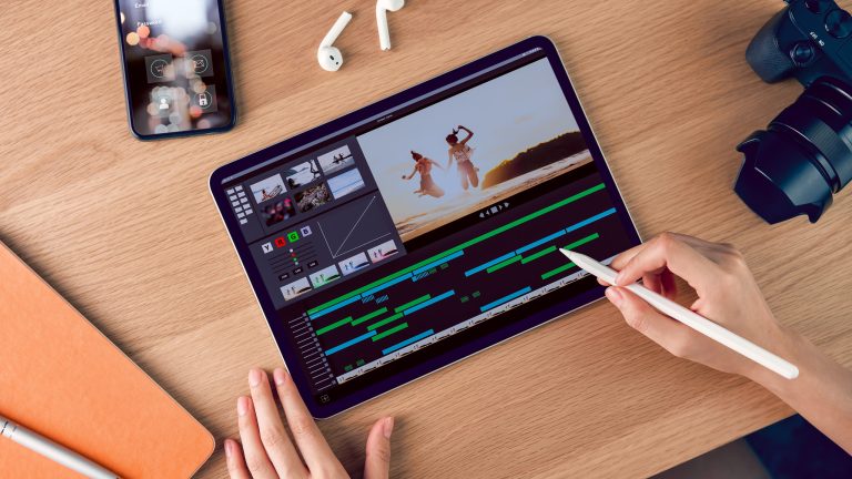 Eine Person sitzt vor einem iPad und hält einen Apple Pencil in der Hand. Auf dem Display ist eine App für Videoschnitt zu sehen.