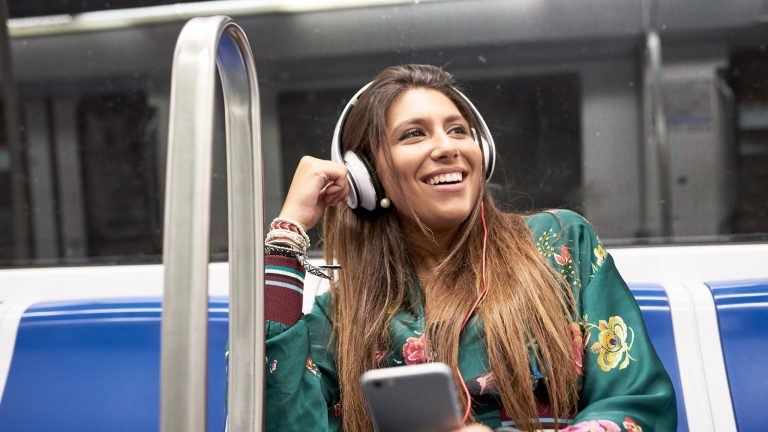 Eine Person fährt in der Bahn und hört dabei Musik von ihrem Smartphone.