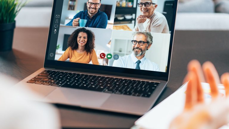 Eine Person sitzt vor einem geöffneten Laptop und ist in einem Meeting.