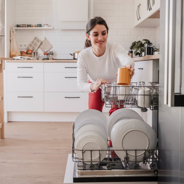 Eine Person räumt eine Tasse in eine Spülmaschine.