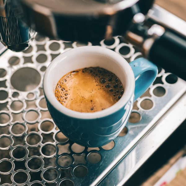 Nahaufnahme einer blauen Espresso-Tasse auf dem Gitter einer Siebträgermaschine.