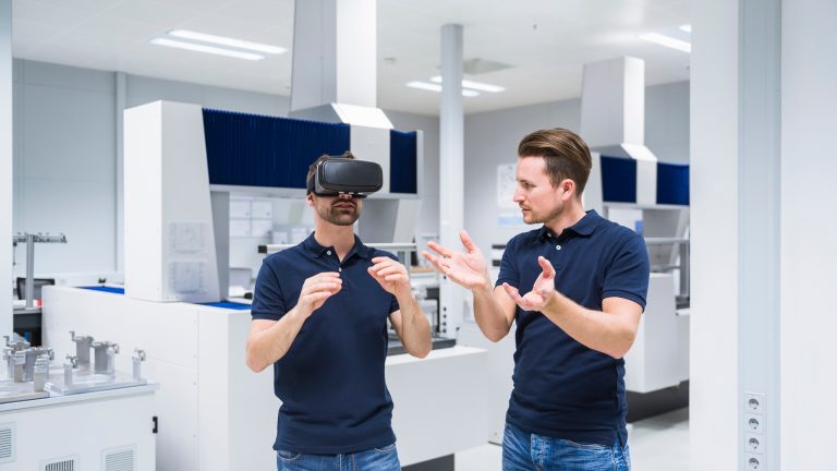 Zwei Personen stehen in einem Tech Lab. Eine der Personen trägt ein Headset.